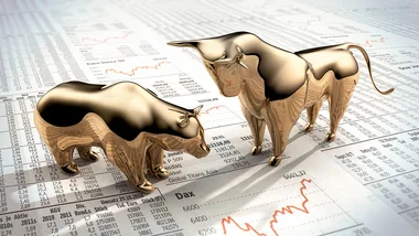 Gold bull and gold bear facing off on newspaper
