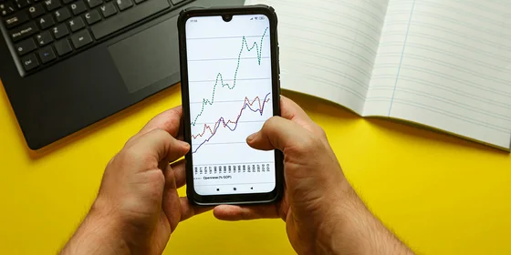 Hands holding a smartphone with stock charts