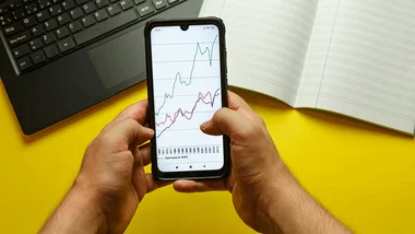 Hands holding a smartphone with stock charts